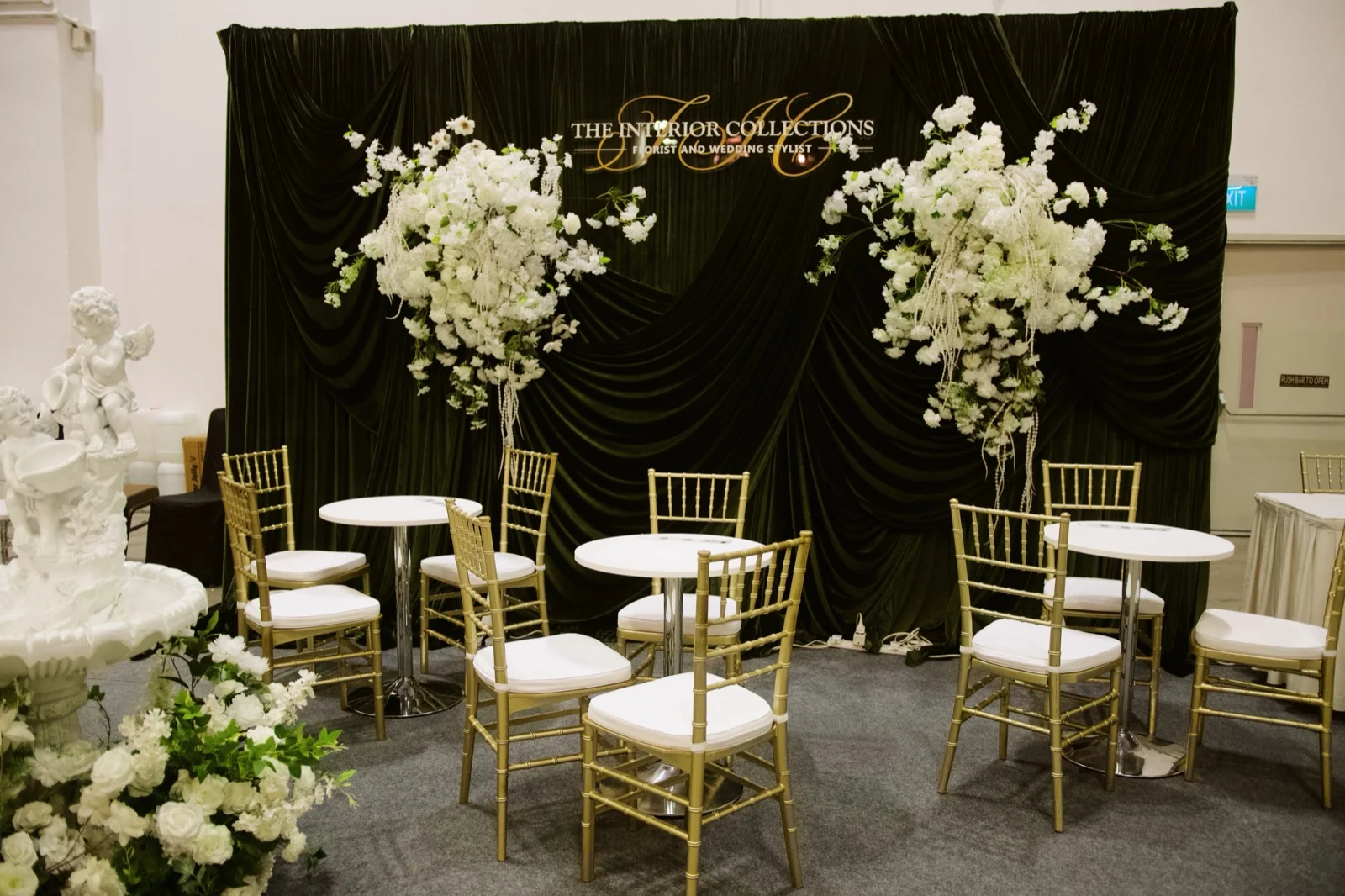 Event space styled by The Interior Collections — dark drapery, gold chiavari chairs and cascading white florals